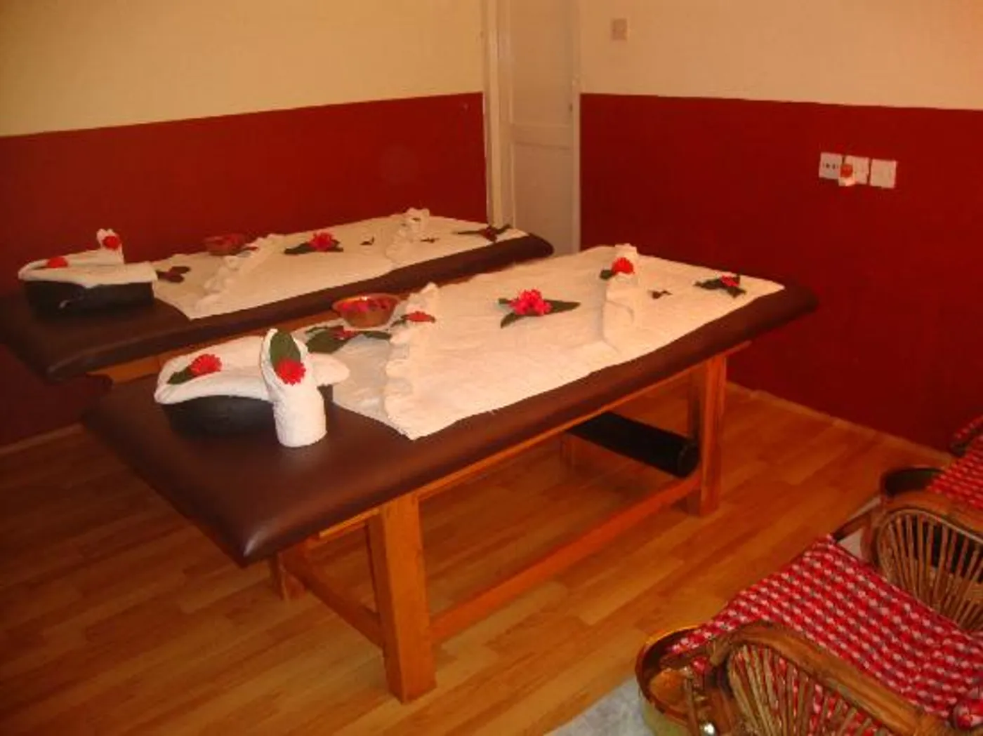 Twin massage beds dressed with white towels and red flowers in the couples room
