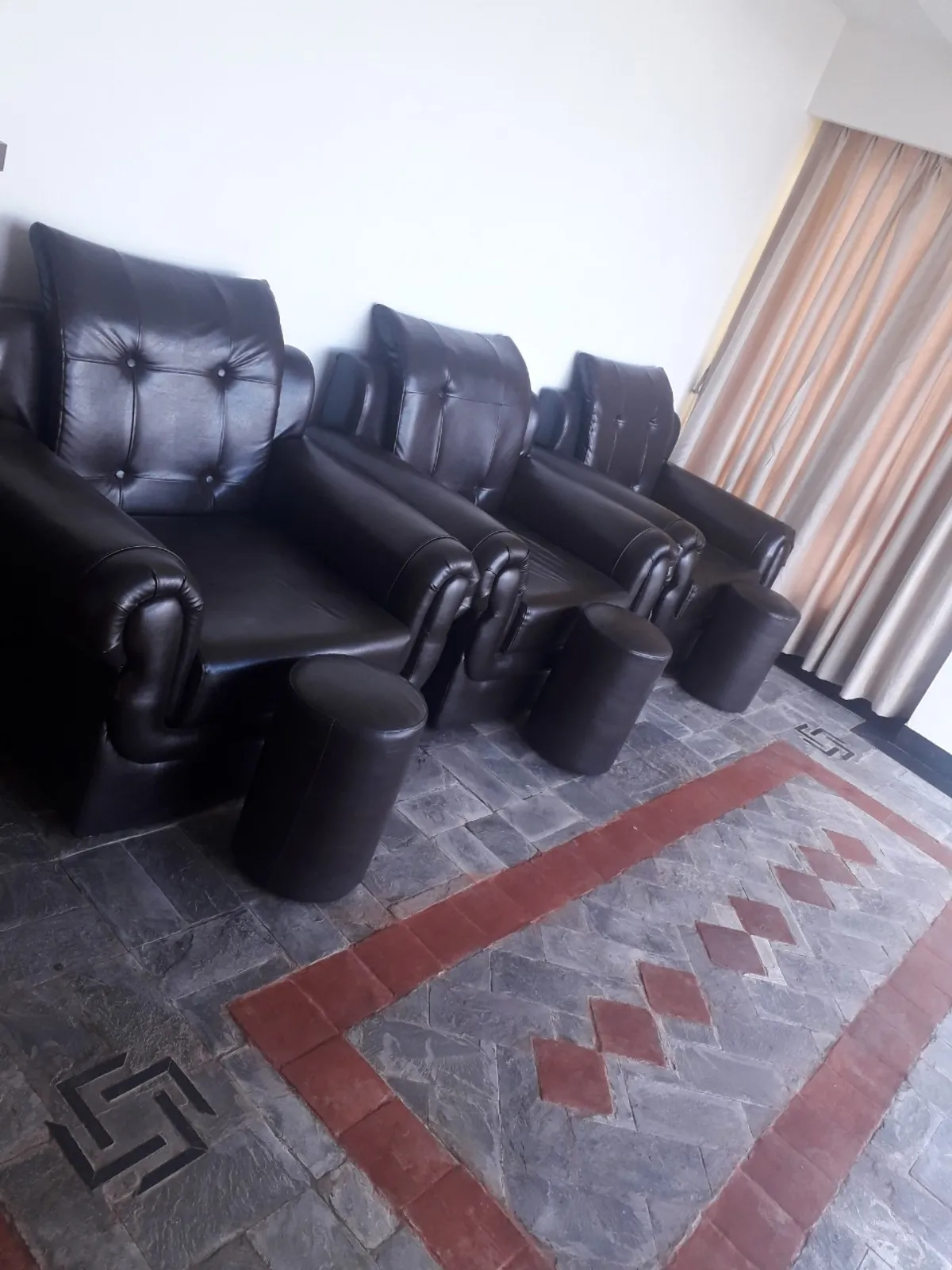 Pedicure chairs lined up on slate flooring with a red ribbon inlay